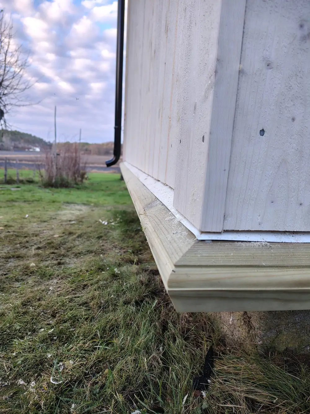 Nederste del av kledningen med beslag og vannbrett over grunnmuren