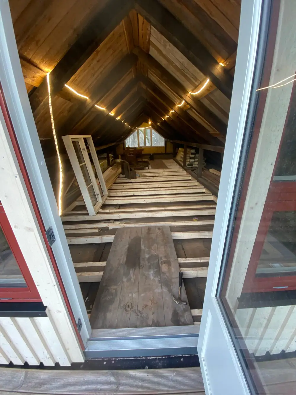 Kaldt loft med åpent bjelkelag og vindu i gavlen, før arbeidet
